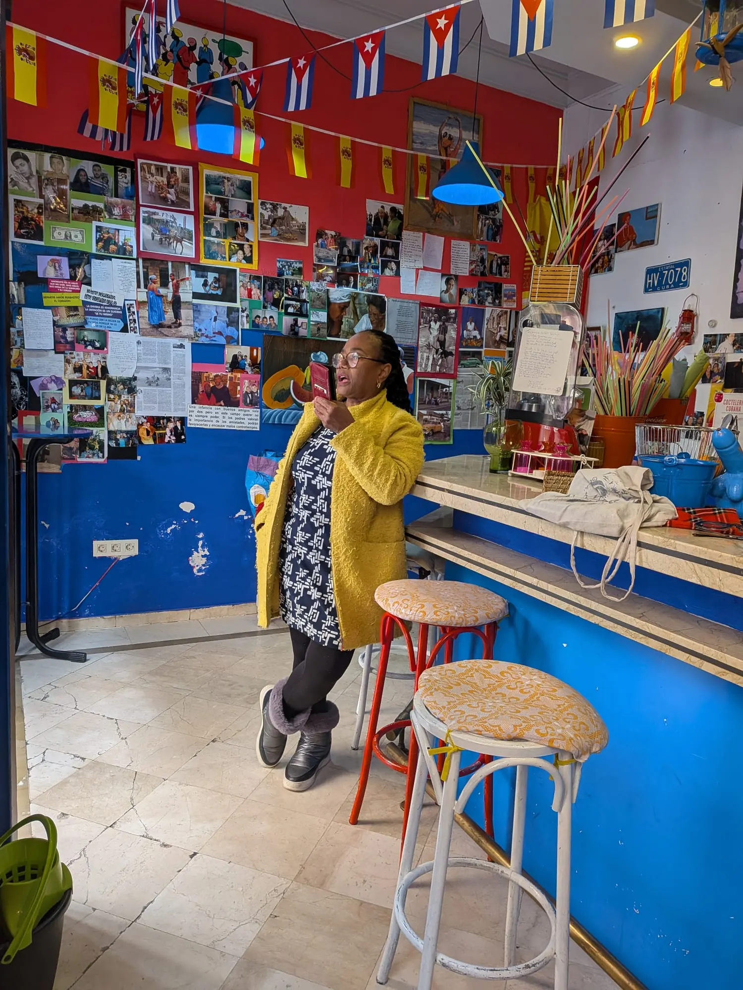 Nancy apoyada en la barra de Casa Cubana, rodeada de fotos y banderas